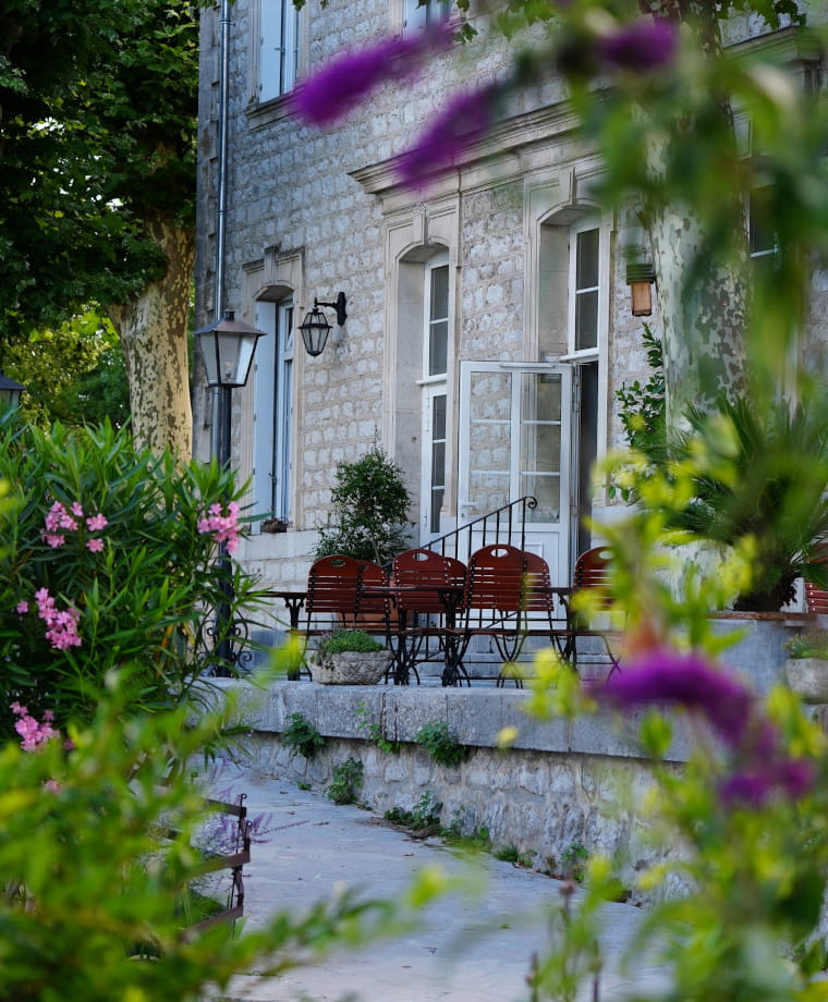 Aperçu de la façade de l'hôtel Savel à travers la végétation du parc