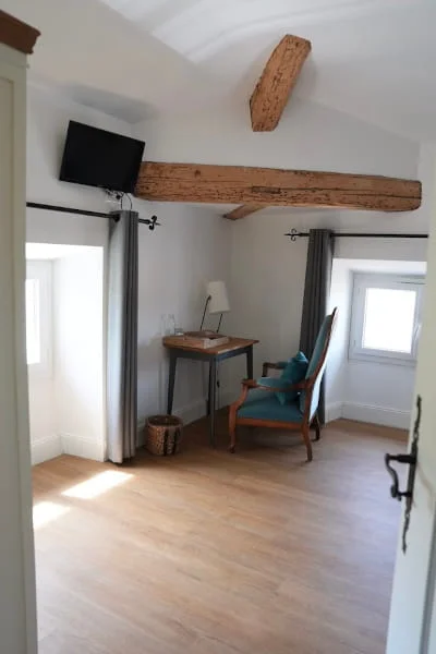Blauer Samtsessel, Schreibtisch und TV unter Sichtbalken des Komfort-Gartenzimmers, Hotel Savel Ruoms