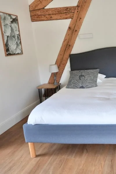 Doppelbett unter Sichtbalken des charmanten Komfort-Gartenzimmers im Hotel Savel Ruoms