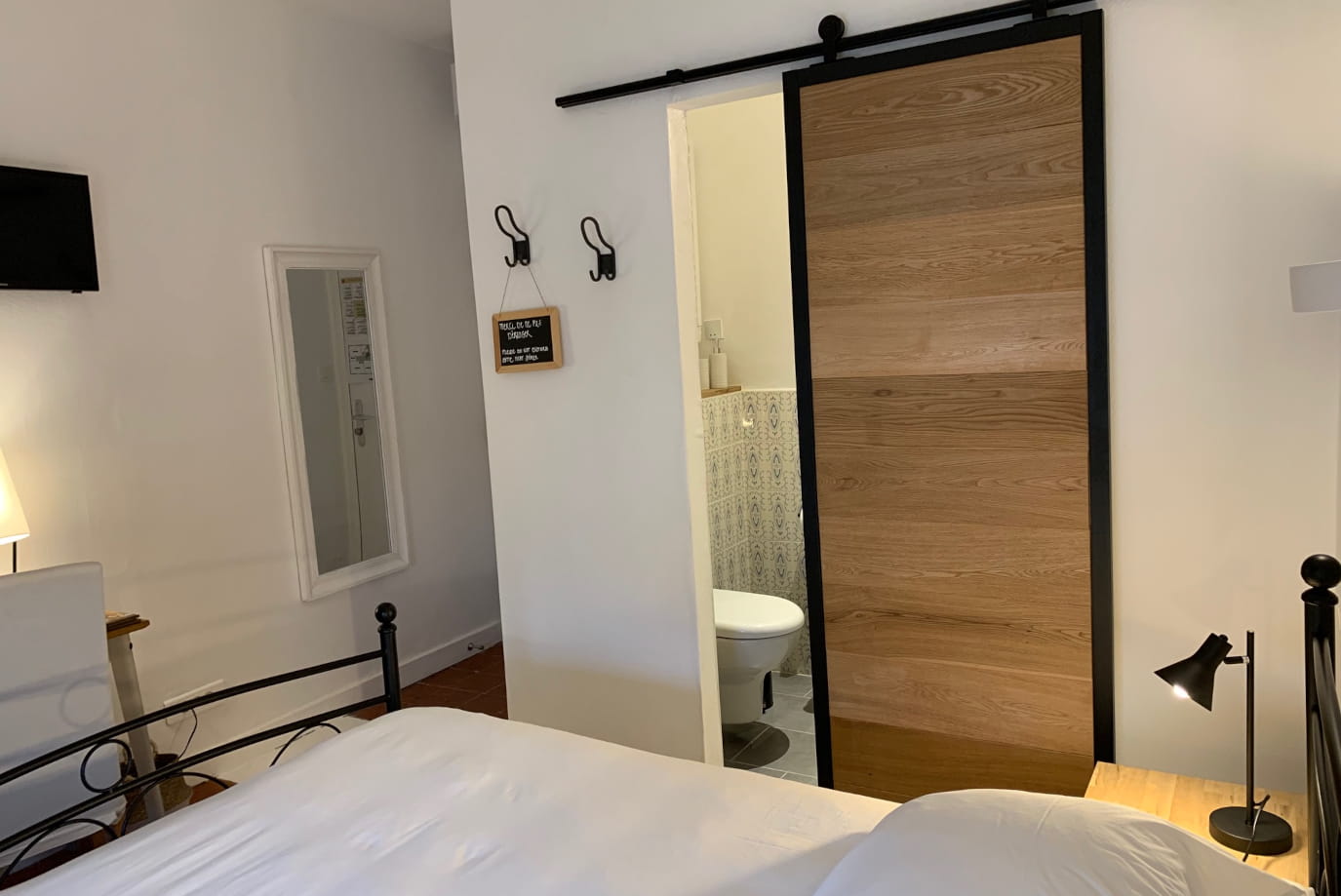 Chambre Confort solo avec porte coulissante en bois et accès salle de bain à l'Hôtel Savel de Ruoms