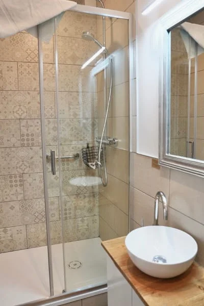 Douche avec carrelage décoratif et vasque sur plan bois de la chambre indépendante à l'Hôtel Savel Ruoms