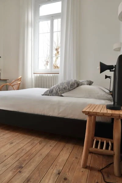 Lit double avec parquet et grande fenêtre lumineuse de la Chambre Premium à l'Hôtel Savel de Ruoms