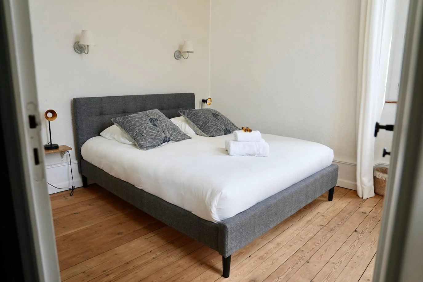 chambre de charme à Ruoms vue depuis la porte avec lit double, serviettes et parquet à l'Hôtel Savel de Ruoms