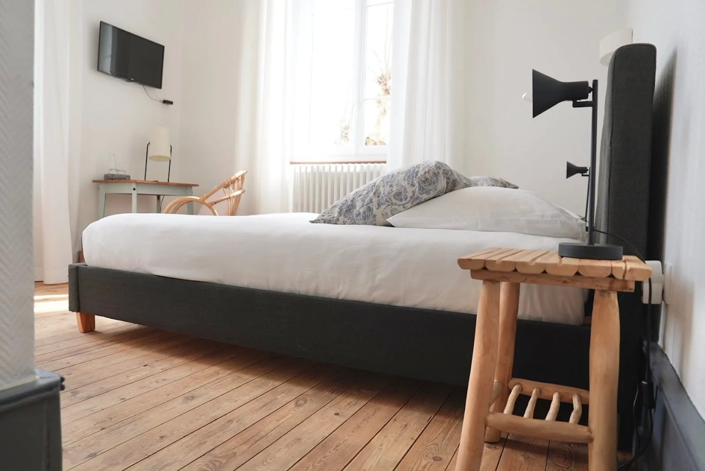 Chambre Premium avec lit double, TV et fauteuil en rotin à l'Hôtel Savel de Ruoms en Ardèche