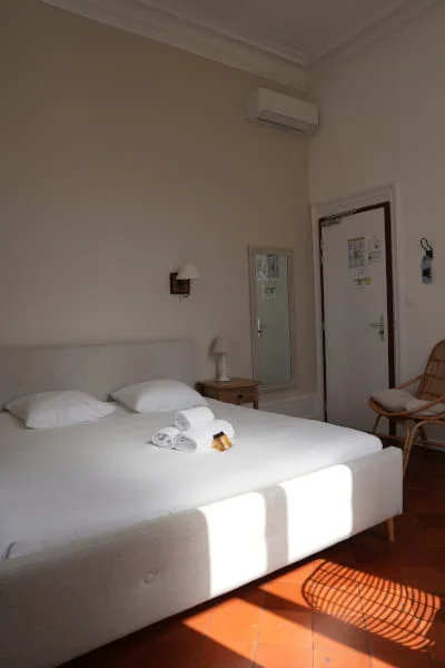 Chambre luxe double avec grand lit blanc, climatisation, sol en tomettes et chaise en rotin, Hôtel Savel à Ruoms proche Vallon-Pont-d'Arc en Ardèche