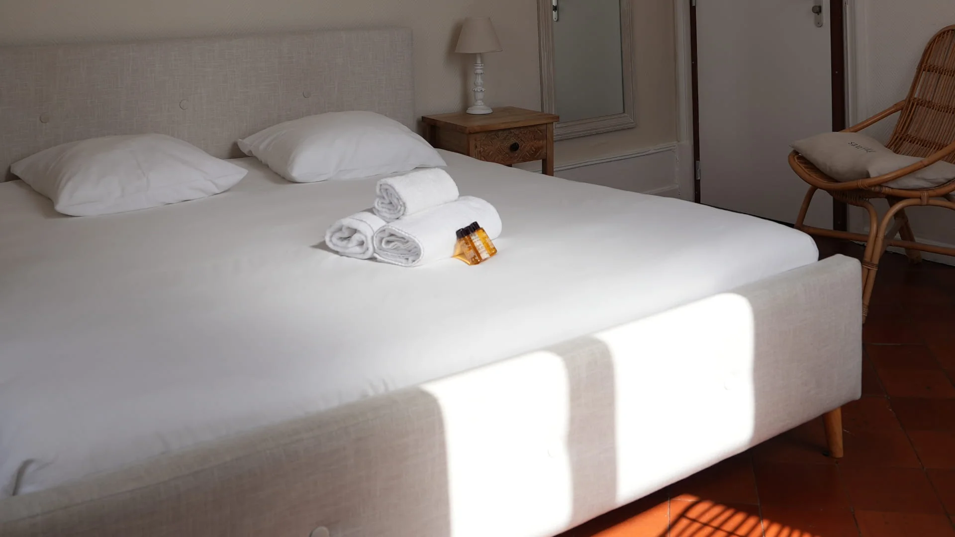 Grand lit double avec linge blanc et serviettes posées, sol en tomettes, chambre luxe de l'Hôtel Savel à Ruoms proche de la Grotte Chauvet en Ardèche