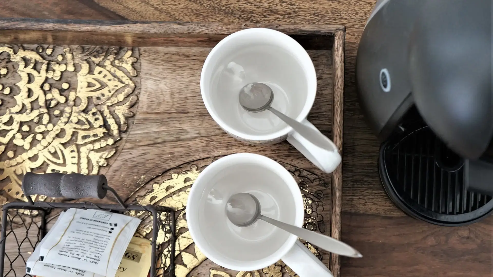 Machine à café Nespresso avec deux tasses blanches et sachets de thé sur plateau en bois sculpté doré, service inclus dans la chambre luxe de l'Hôtel Savel à Ruoms
