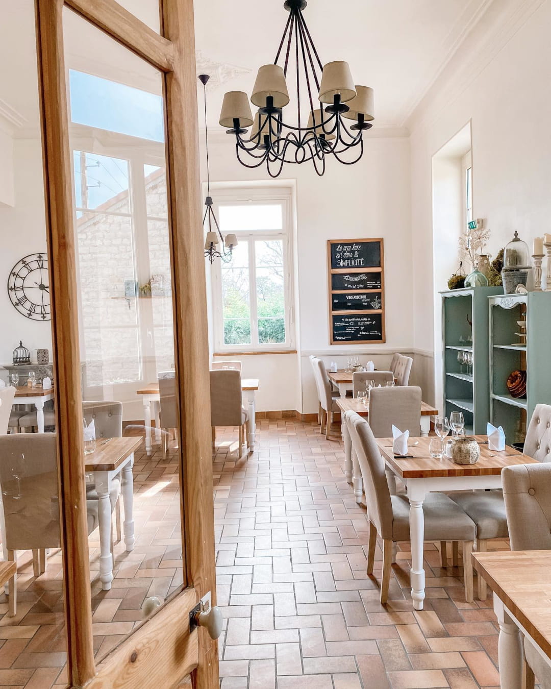 Salle lumineuse du restaurant intérieur de l'Hôtel Savel à Ruoms en Ardèche, avec son ardoise "Le vrai luxe est dans la simplicité" - FAQ de l'Hôtel Savel