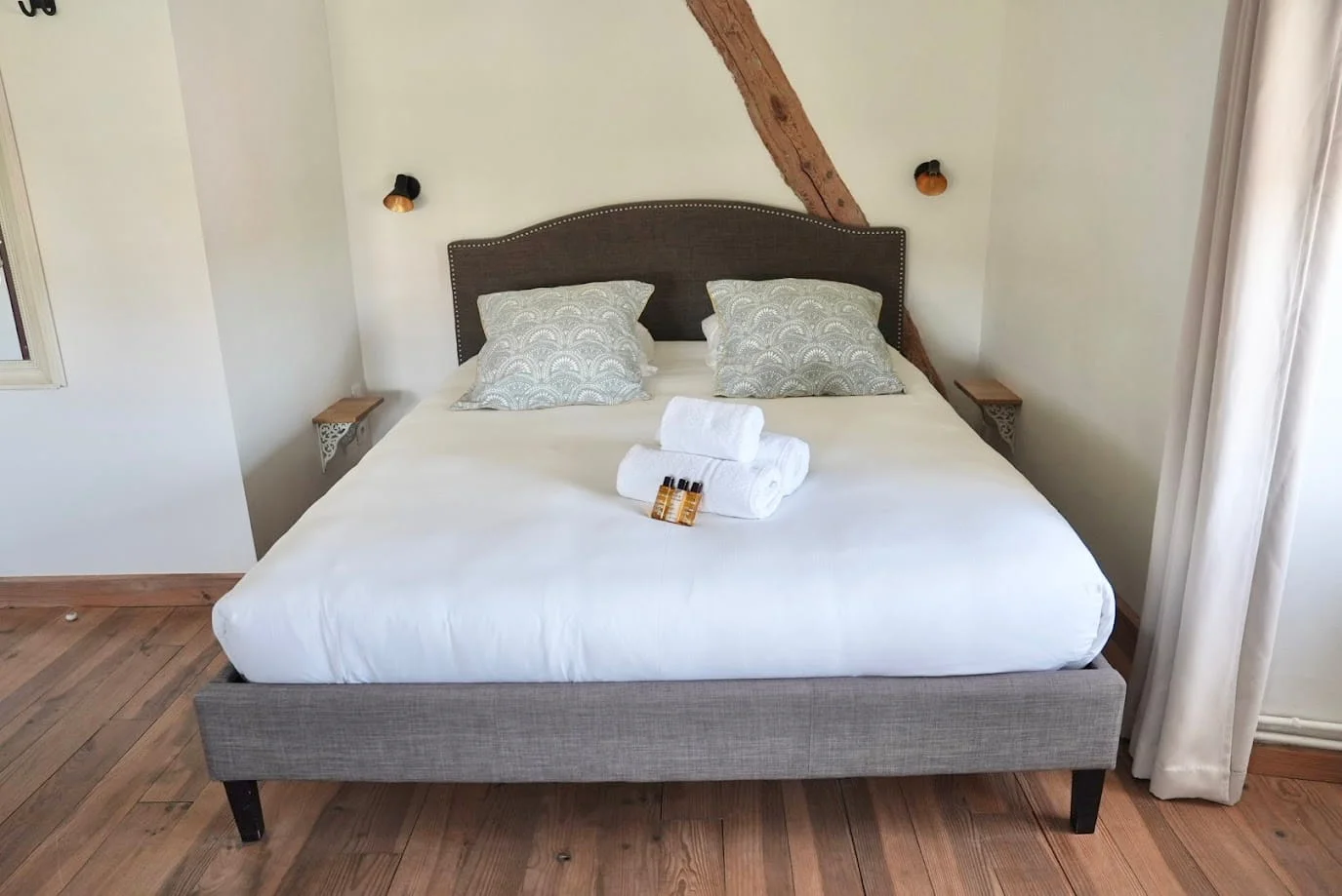 Overview of the Comfort Suite with exposed beams and rattan chair at Hotel Savel Ruoms, Ardèche