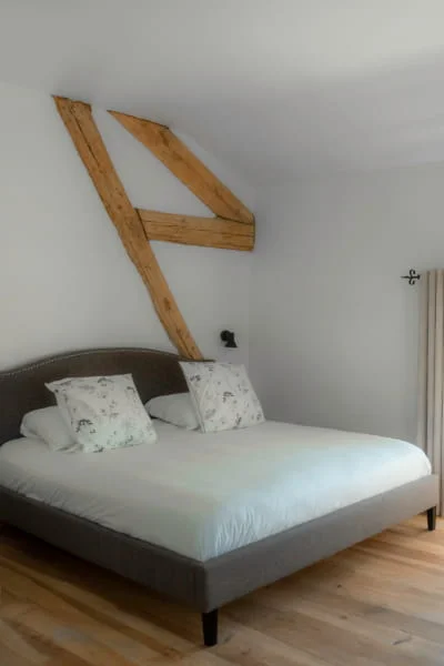 Lit double sous poutres apparentes et parquet de la Suite Confort climatisée à l'Hôtel Savel de Ruoms