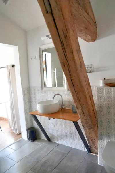 Salle de bain avec vasque, plan bois et poutre apparente de la Suite Confort à l'Hôtel Savel de Ruoms