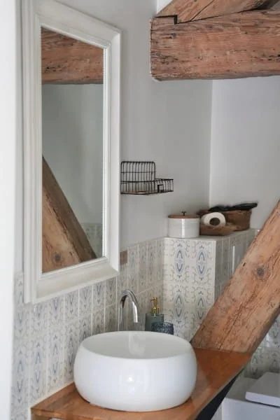 Vasque ronde sur plan bois et poutres apparentes de la salle de bain de la Suite Confort à l'Hôtel Savel Ruoms