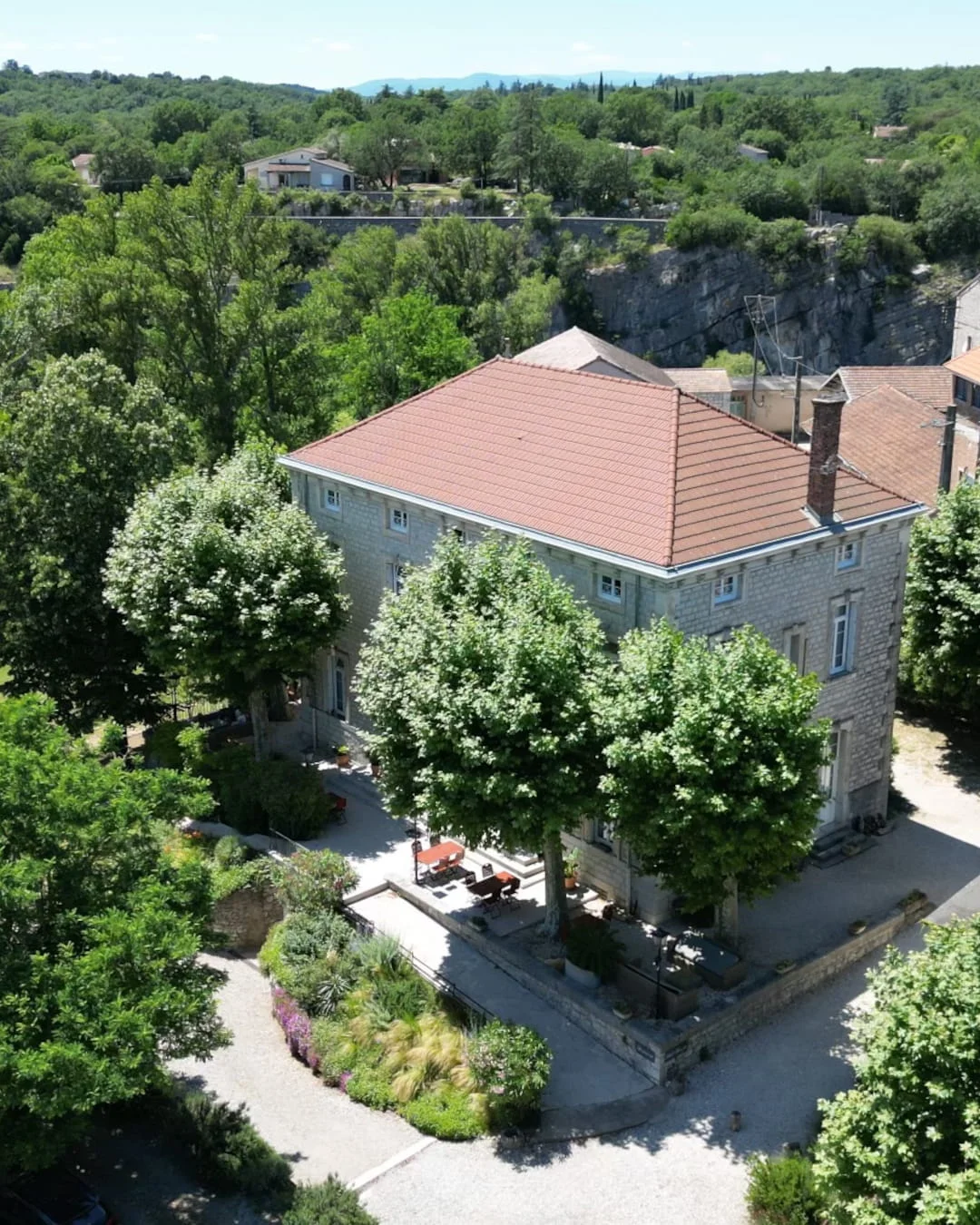 Vue aérienne de l'Hôtel Savel à Ruoms, ancienne brasserie du XIXᵉ siècle nichée au pied de la falaise en Ardèche